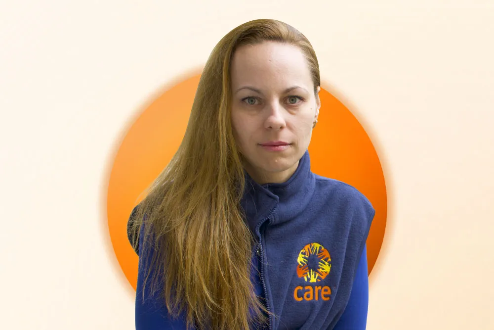 A portrait of a blond Ukrainian woman wearing a CARE vest.
