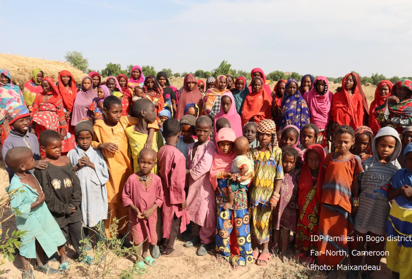 A diverse group of women and children pose together, looking at the camera.