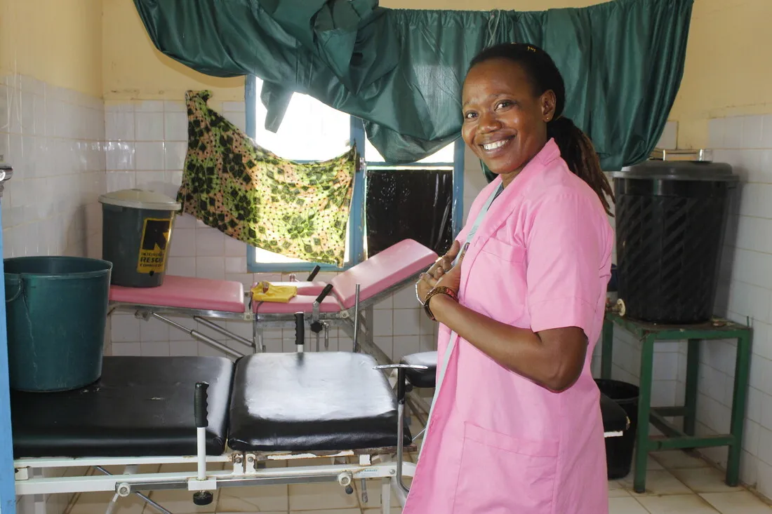 A smiling healthcare worker in pink scrubs at a CARE-supported clinic in Chad.