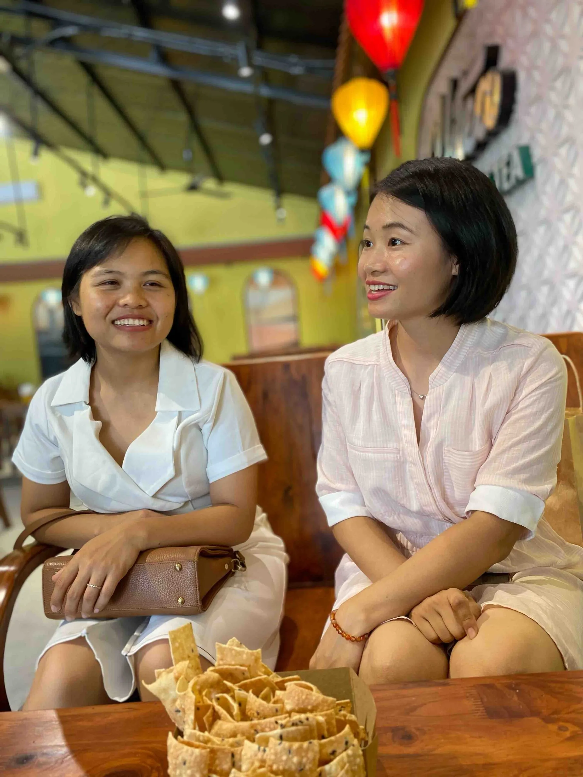 Medium image of two seated, dark-haired women smiling.